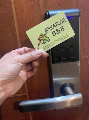A hand holding a business card with a bird illustration and the text "PIKAFLOR B&B".