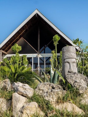 A building with a triangular roof and a stone statue in the foreground. - Belizima Eco Resort (Sarteneja)