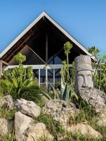 A building with a triangular roof and a stone statue in the foreground.