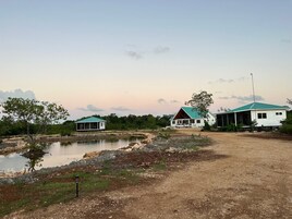 Propiedad rural con dos casas, un estanque y un sendero de tierra.