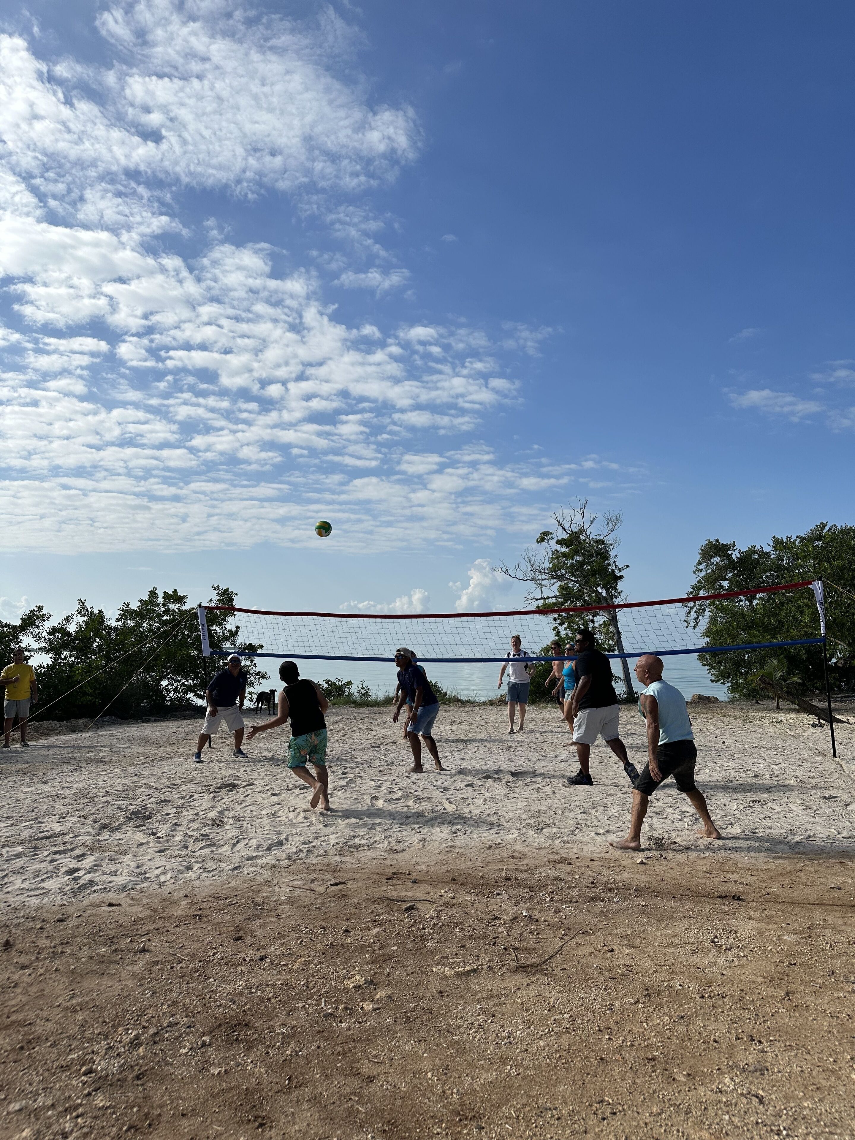 Een zandvolleybalveld met spelers en een net.