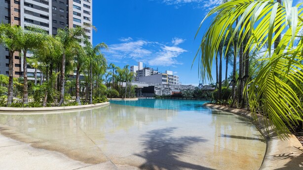 A swimming pool surrounded by palm trees and buildings. - Piscine  (São Paulo)