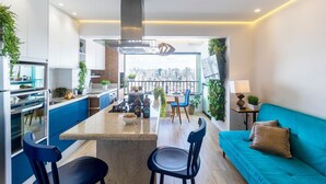 A modern kitchen with a central island, blue chairs, and a teal sofa. - Piscine  (São Paulo)