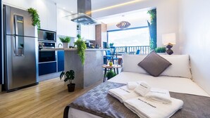 A modern hotel room with a kitchenette, a balcony with a view, and a neatly made bed with towels. - Piscine  (São Paulo)