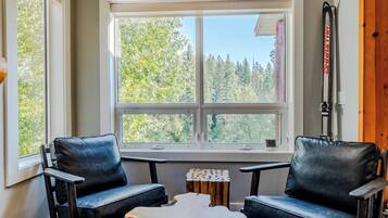 A room with two leather chairs, a small table, and a window with a view of trees.