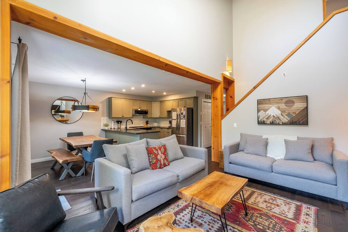 A spacious living area with a dining table, two sofas, a coffee table, and a kitchen in the background.