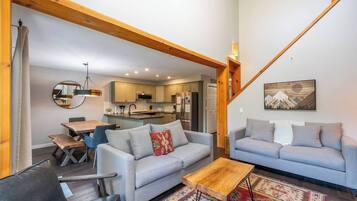 A spacious living area with a dining table, two sofas, a coffee table, and a kitchen in the background.