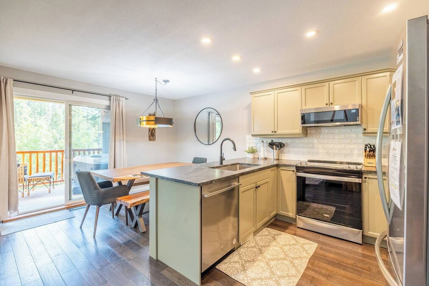 A modern kitchen with a central island, stainless steel appliances, and a view to a balcony.
