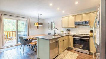 A modern kitchen with a central island, stainless steel appliances, and a view to a balcony.