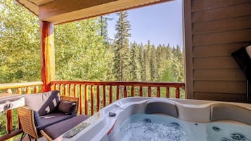 A hot tub on a wooden deck with a view of a forest.