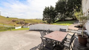 An outdoor patio with a table and chairs, a potted plant, and a view of a hilly landscape. - Pyllau Farm (Llandudno)