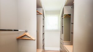 A walk-in closet with a mirror, wooden hangers, and a metal rack. - Pyllau Farm (Llandudno)