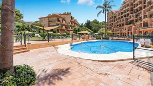 A resort with a swimming pool, outdoor seating, and multiple-story buildings.