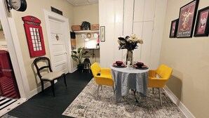 A dining area with a round table, two yellow chairs, a vase with flowers, and a red telephone booth. - Royal European Corner to a Romantic Gateaway by Downtown-Houston, Heights & WOMH (Houston)