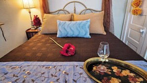 A neatly made bed with a decorative headboard, a bedside table with a lamp and flowers, and a tray with a wine glass. - Royal European Corner to a Romantic Gateaway by Downtown-Houston, Heights & WOMH (Houston)