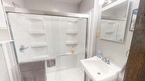A modern bathroom with a glass-enclosed shower, a white sink, and a mirror above the sink. - Garfield Park Stay - 5 min to Fountain Square (Indianapolis)