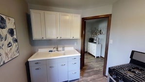 A kitchen with white cabinets, a sink, and a stove. - Garfield Park Stay - 5 min to Fountain Square (Indianapolis)