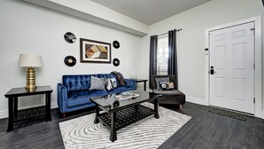 Ein modernes Wohnzimmer mit einem blauen Sofa, einem Couchtisch und einer weißen Tür.