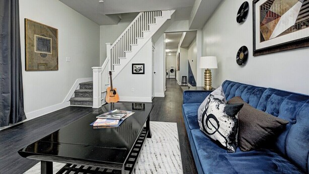 Ein modernes Wohnzimmer mit Treppe, einem blauen Sofa und einem Couchtisch mit Büchern.