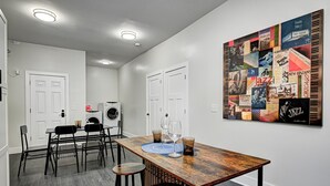 Ein Essbereich mit einem Holztisch, Barhocker und einem an der Wand hängenden Poster.