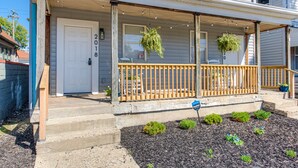Ein Wohnhaus mit Veranda, einer Tür mit der Aufschrift "2018" und einem kleinen Garten mit Mulch und Pflanzen.