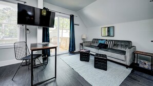 Una sala de estar moderna con un sofá, televisor, mesa de comedor y una silla.