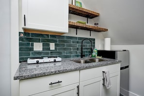 A kitchen with white cabinets, a granite countertop, a built-in stove, a stainless steel sink, and a refrigerator.