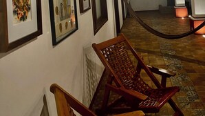A hallway with framed artwork on the walls, a wooden chair, and a tiled floor. - HOTEL CASA TERESA GALERIA CAFE  (Juchitan de Zaragoza)