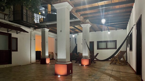 A spacious indoor area with tiled flooring, white pillars, and a staircase leading to an upper level. - HOTEL CASA TERESA GALERIA CAFE  (Juchitan de Zaragoza)