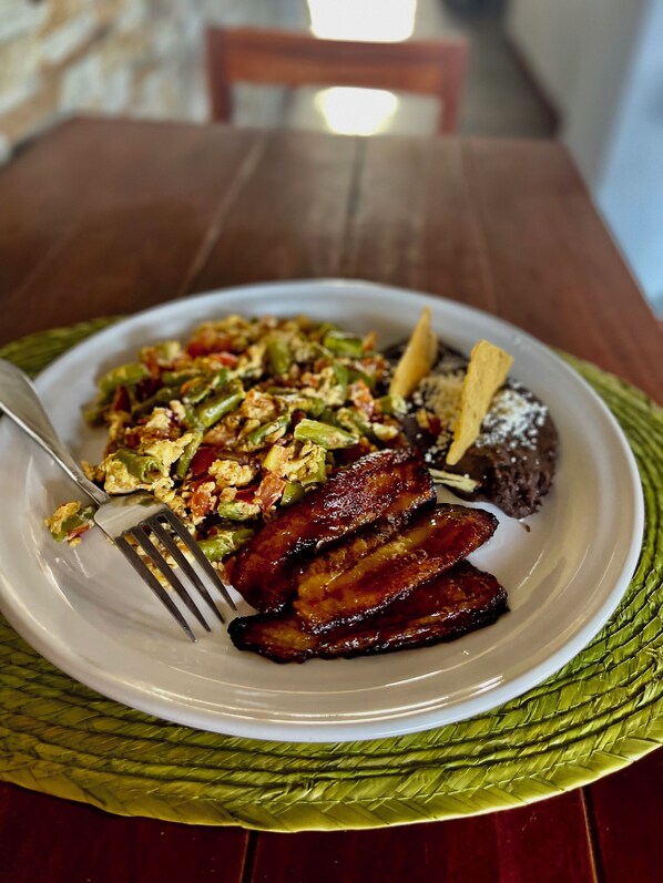 A plate of food with eggs, green beans, and a piece of meat on a woven placemat.