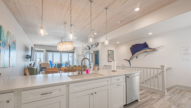A spacious kitchen with white cabinetry, a large island, and a dishwasher.