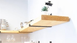 Eine Küche mit Holzböden, die Teller und Gläser, eine Kaffeemaschine und eine kleine Pflanze beherbergt.