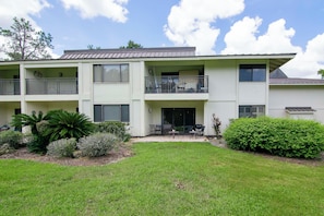 A two-story building with a flat roof, balconies, and a small patio area with outdoor furniture. - First Floor 2bd/2ba Fully Remodeled Condo in Saddlebrook (Wesley Chapel)