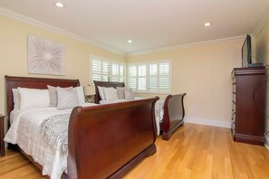 A bedroom with a large bed, a dresser, and a television on a stand.