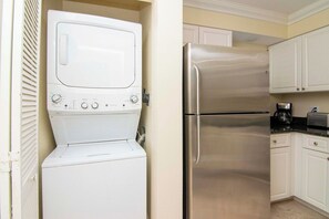 A compact kitchen with a stainless steel refrigerator and a white washer-dryer unit. - Saddlebrook 1st Floor 2 bd/2 ba Fully Remodeled (Wesley Chapel)