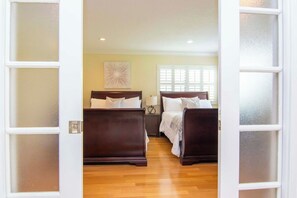 A hotel room with two beds, a wooden floor, a wall-mounted artwork, and a window with blinds. - Saddlebrook 1st Floor 2 bd/2 ba Fully Remodeled (Wesley Chapel)