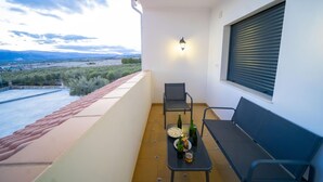 A balcony with a table set for two, a chair, and a window with blinds. - El Refugio de El Espilo in Almería (Andalusia) (Lúcar)