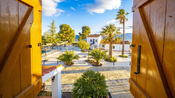 A courtyard with a white building, palm trees, and a clear blue sky. - El Refugio de El Espilo in Almería (Andalusia) (Lúcar)