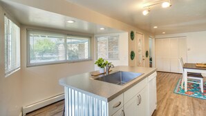 A kitchen with a central island, white cabinets, and a window with blinds. - Grand Junction Vacation Rental w/ Patio & Grill! (Grand Junction)