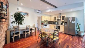 A modern kitchen with wooden cabinets, a stainless steel refrigerator, and a dining area with a round table and chairs.
