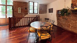 A dining area with a round table, chairs, and a brick wall.