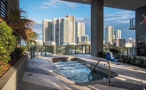 A rooftop pool with a city view, surrounded by greenery and modern architecture.