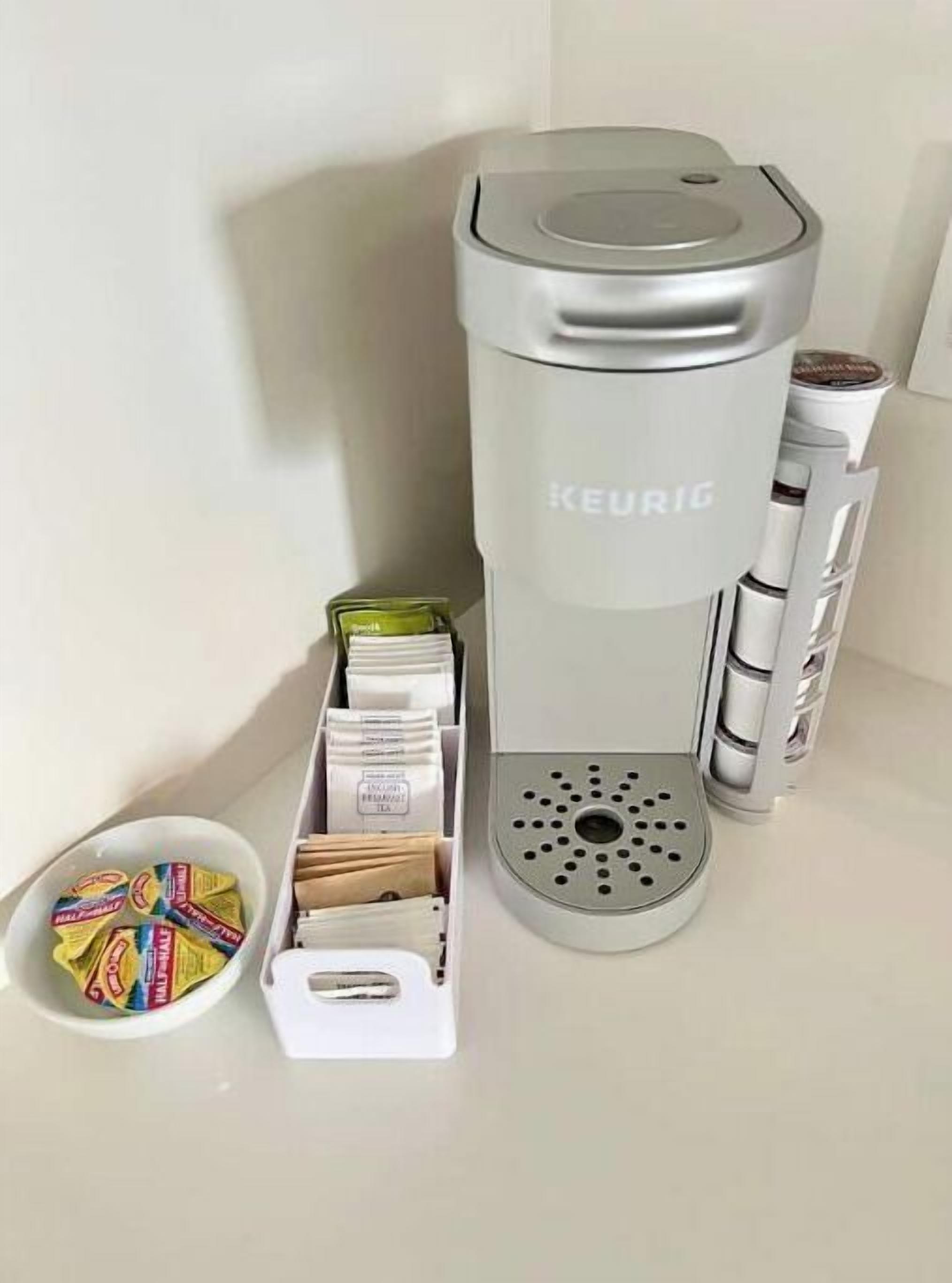 A Keurig coffee maker with a water reservoir, a coffee pod holder, and a cup holder.
