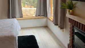Una camera da letto con un letto, un tappeto nero, un camino e un televisore appeso al muro.