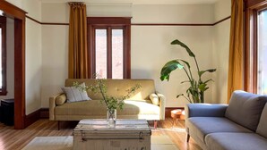 A living room with a beige sofa, a blue sofa, a vintage suitcase, and a plant. - At Leo's by Maison Dudley (Lac-Mégantic)