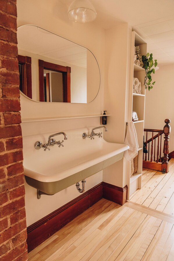 A bathroom with a large mirror, a white sink, and a wooden floor.
