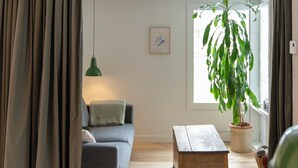 A cozy living room with a grey sofa, a wooden coffee table, and a large potted plant. - The Loft by Maison Dudley (Lac-Mégantic)