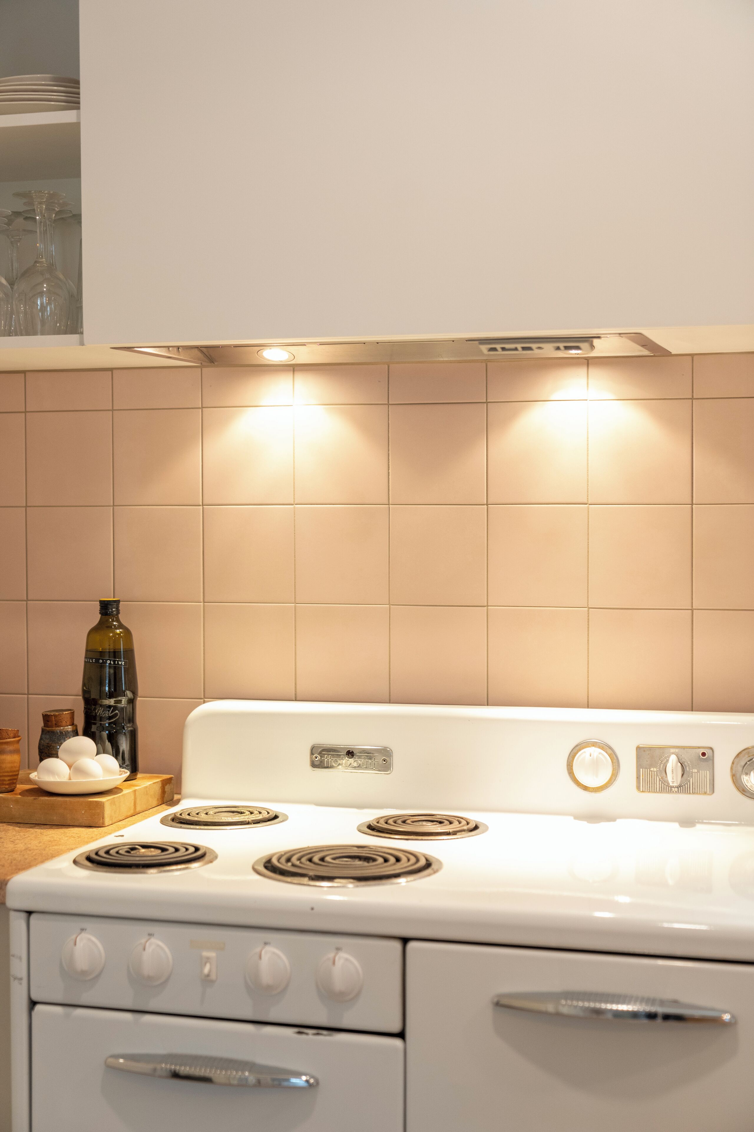 A kitchen with a white stove, a wooden cutting board with eggs, and a bottle of oil.