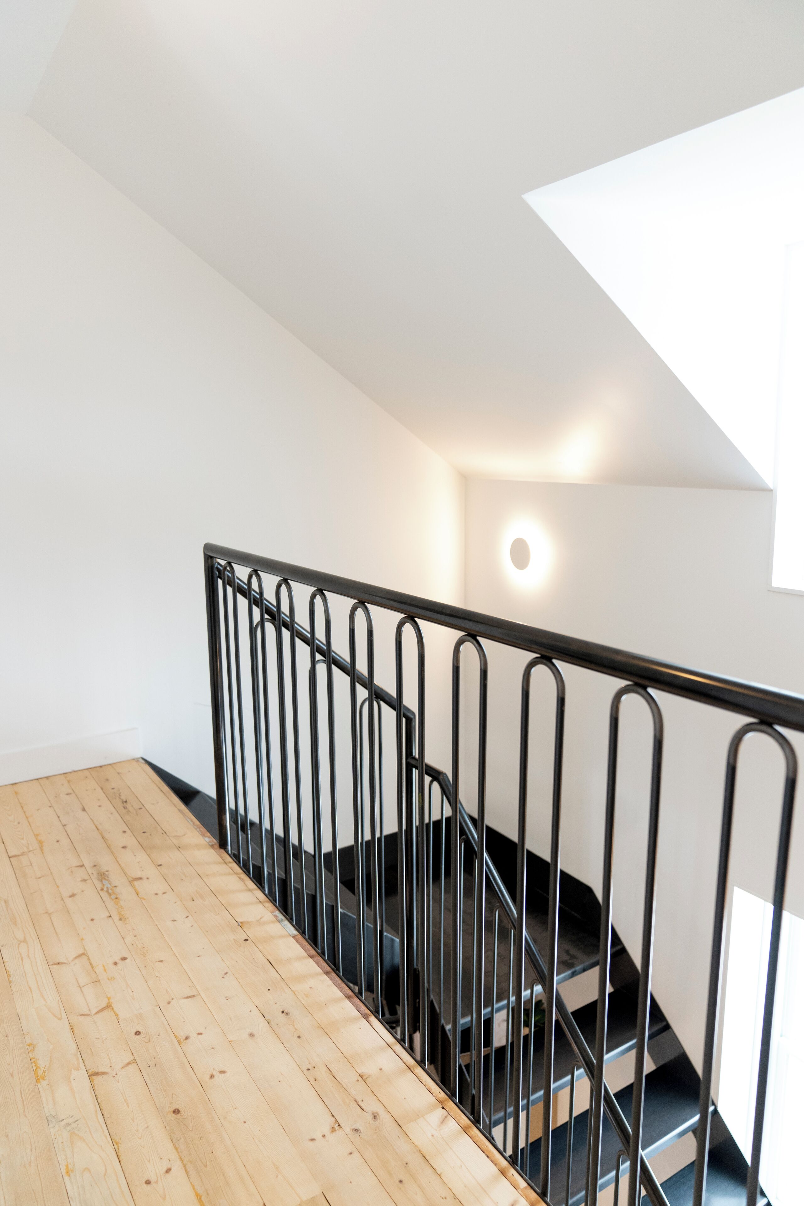 Un plancher en bois mène à un escalier doté d’une rampe en métal.