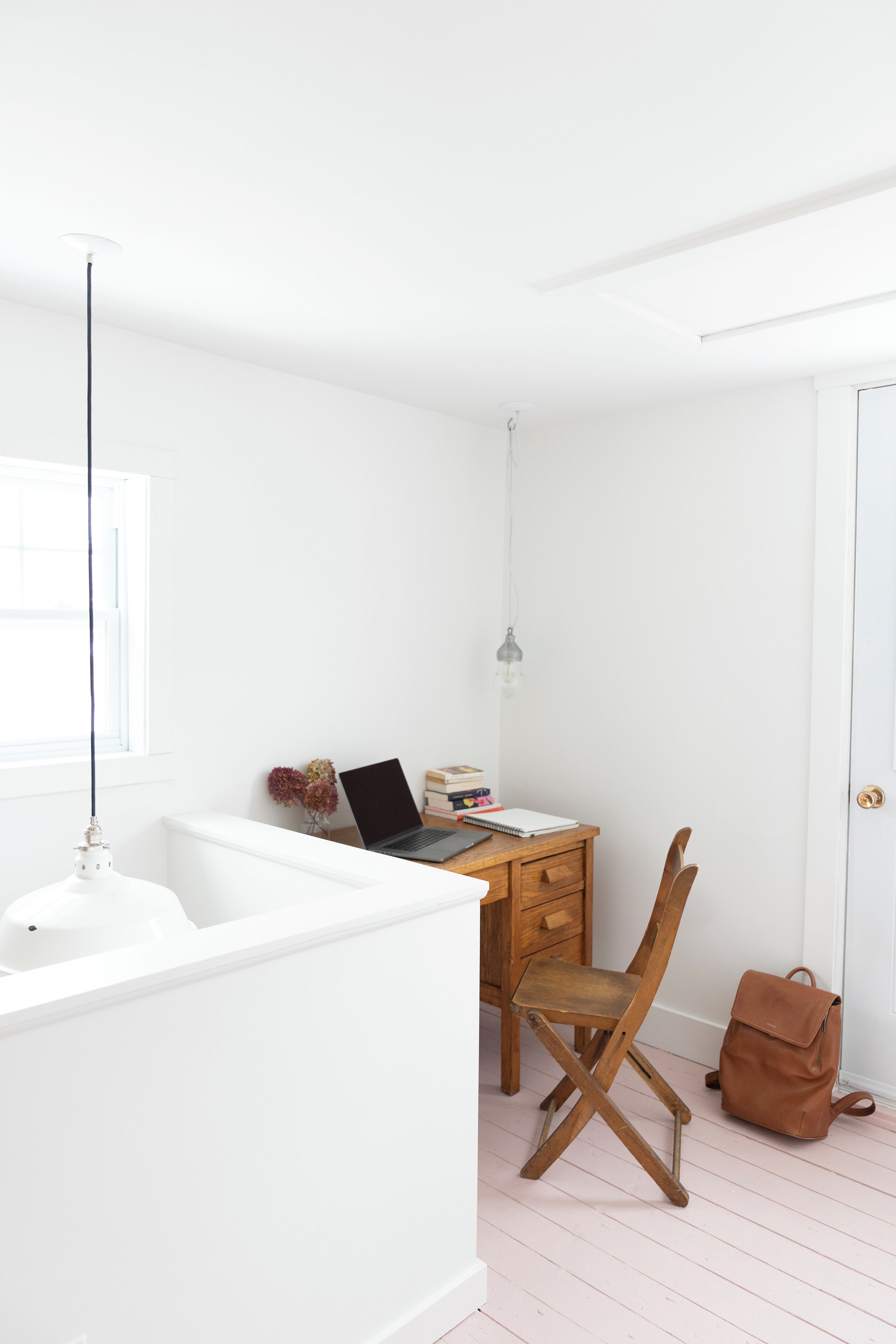 A white room with a wooden desk, a laptop, and a chair.